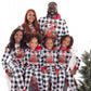 Family of six wearing matching black and white checkered pajamas with red accents, standing in front of a small Christmas tree on a white background.